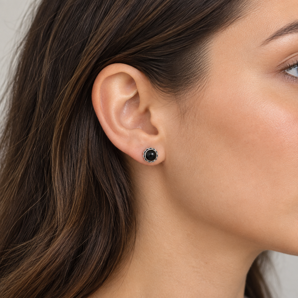 Pendiente negro de 7 mm puesto en la oreja de una chica