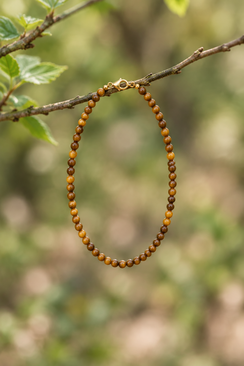 Pulsera de ojo de tigre colgada de una ramita de árbol