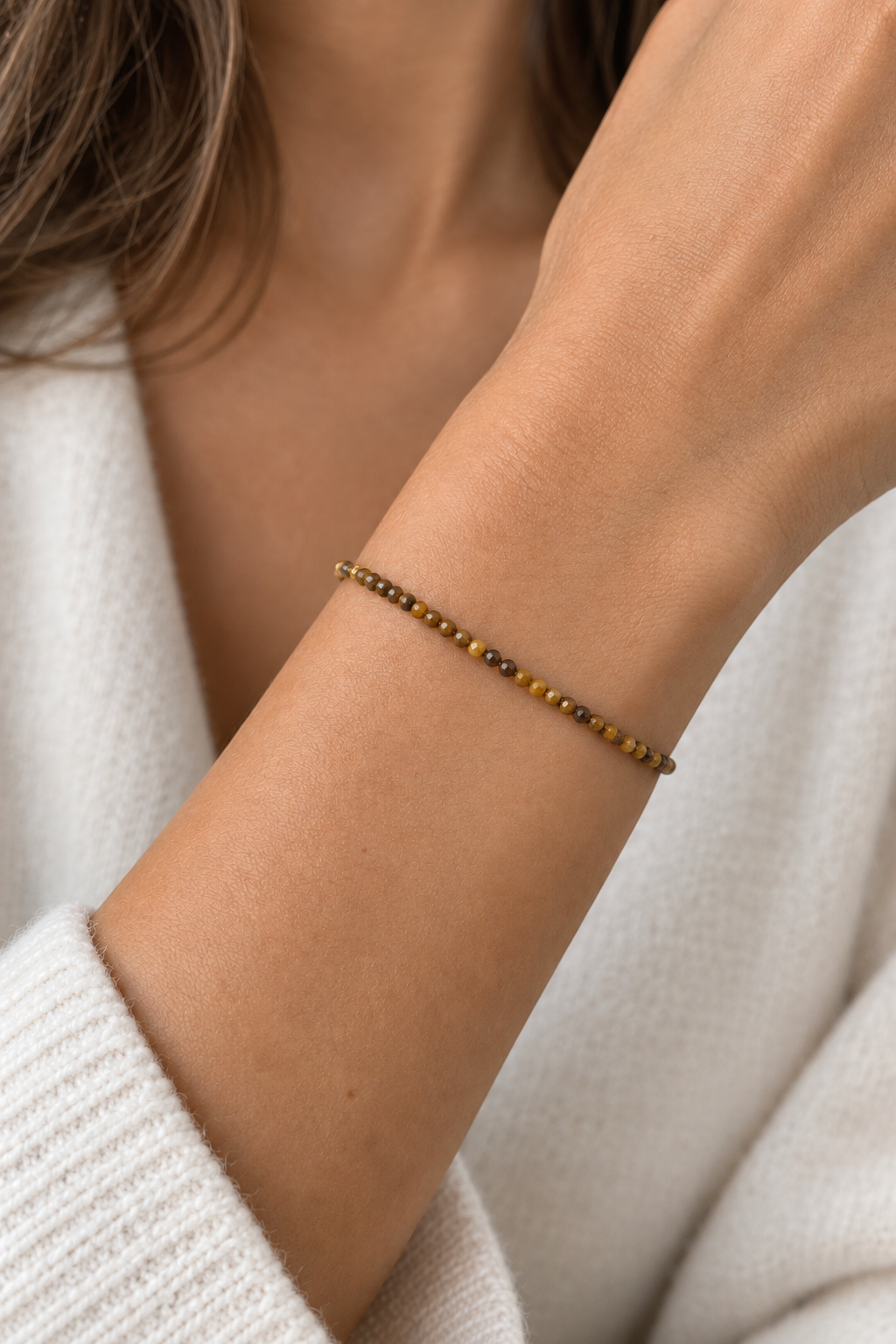 Pulsera de ojo de tigre con cierre dorado en la muñeca de una mujer