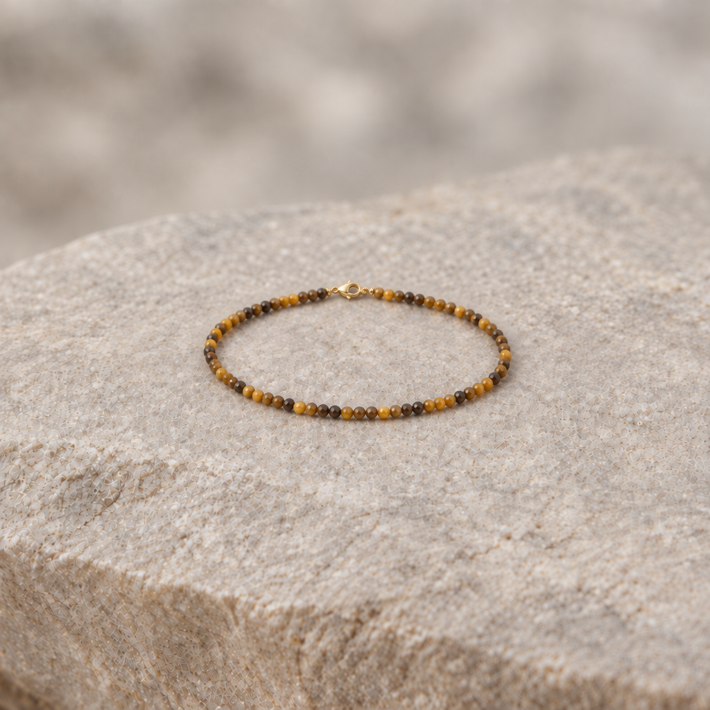 Pulsera de ojo de tigre con cierre dorado sobre piedra